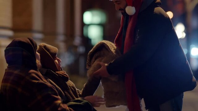 A man in a Santa hat warmly gives a soft blanket to a homeless person on a cold Christmas night, spreading joy and kindness in the community as lights twinkle in the background