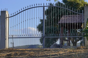 Obraz premium A classic wrought iron gate, galvanized and framed by a serene Italian countryside with rolling hills, seems to guard the peace.
