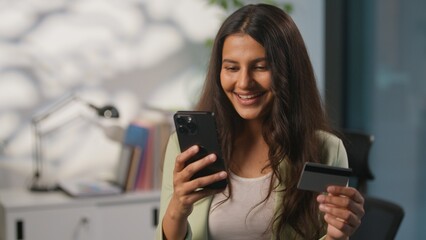 Smiling carefree Indian informal business woman enjoying buying internet mobile phone store...