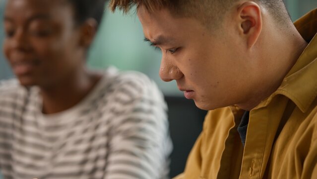 Asian concentrated businessman Korean business man using digital tablet device gadget online browsing talking serious with African American businesswoman in office startup two diversity colleagues