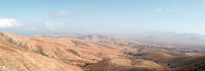 Panoramic view from Guise and Ayose viewpoint in Fuerteventura. Arid mountains and valleys extend under a clear blue sky, showing the volcanic landscape of the Canary Islands.