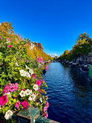 A beautiful view of an Amsterdam canal, with blooming flowers adding a touch of color and charm to the urban landscape
