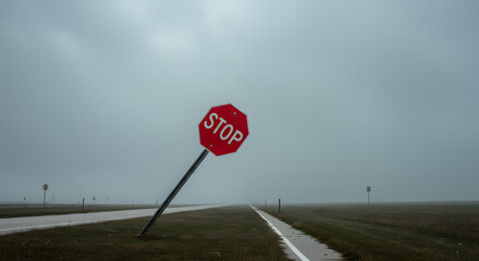 Bent stop sign leaning sideways in foggy rural landscape  
