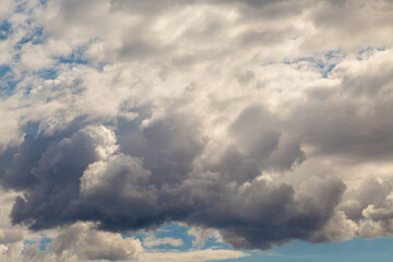 Obraz premium Light breaks through a dense veil of gray clouds close-up.