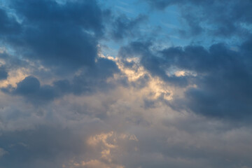 Obraz premium Sunlight reflects the texture of clouds high in the sky during the blue sunset hour before twilight.