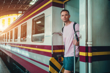 traveler guy boarding train at busy railroad station, young man with backpack starting journey on railway platform