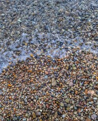 Calm ocean waves gently washing over stones at the beach