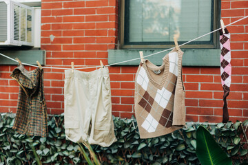 Laundry hanging outside on a clothesline next to a brick wall in an urban area during a sunny day