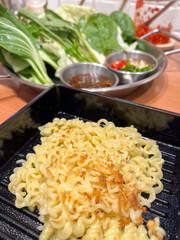 Crispy garlic noodles with fresh greens and dipping sauce, warm savory comfort meal with vibrant herbs