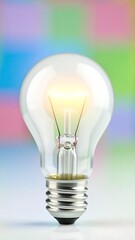 Illuminated lightbulb against a blurred colorful background