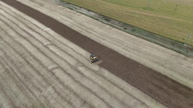 Aerial drone footage of a combine harvester cutting a golden wheat field, showcasing modern agriculture, grain harvest, rural landscape, and seasonal farming productivity.