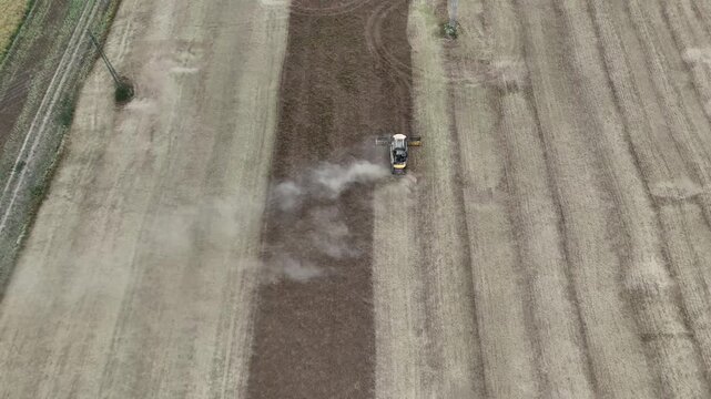 Aerial drone footage of a combine harvester cutting a golden wheat field, showcasing modern agriculture, grain harvest, rural landscape, and seasonal farming productivity.