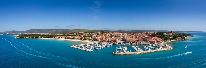 Obraz premium Panoramic aerial view of a vibrant coastal town with a bustling marina filled with yachts under a clear blue sky