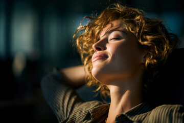 Woman enjoying the sunshine. Relaxing with eyes closed and smile on her face, taking a moment for herself.