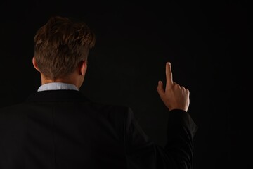 Man touching something on black background, back view