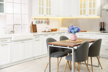 Dining table, chairs and floral decor in kitchen. Interior design