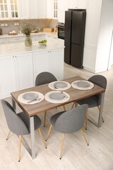 Kitchen interior with dining table, place setting and grey chairs