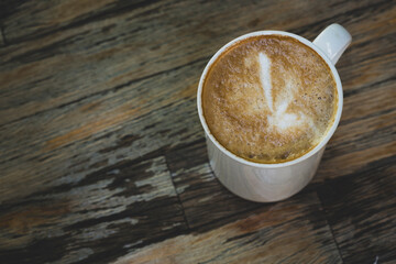 Latte in White Cup on Wooden Table. Cozy Latte Coffee Cup on Wooden Background. Morning Latte in Ceramic Mug on Wood Table.