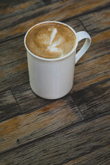 Latte in White Cup on Wooden Table. Cozy Latte Coffee Cup on Wooden Background. Morning Latte in Ceramic Mug on Wood Table.