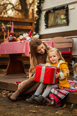 happy family of mother and daughter celebrating Christmas near the trailer with Christmas decorations