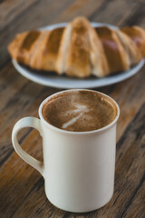 Latte Coffee and Croissant on Wooden Table. Cup of Latte and Croissant Morning Snack. Delicious Latte with Fresh Croissant on Table. Fresh Croissant with Cup of Latte.