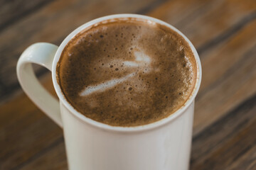 Latte in White Cup on Wooden Table. Cozy Latte Coffee Cup on Wooden Background. Morning Latte in Ceramic Mug on Wood Table.