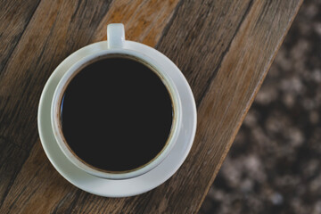 Cup of coffee on wooden table. Hot coffee in a cup on rustic wooden surface. Warm beverage on wooden background.