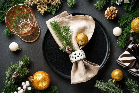 Christmas food background. Craft plate with golden christmas decorations at black.