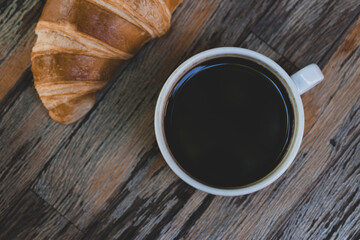 Fresh croissant and hot coffee. Cup of coffee and croissant. Breakfast with coffee and croissant. Cup of coffee with croissant on table.