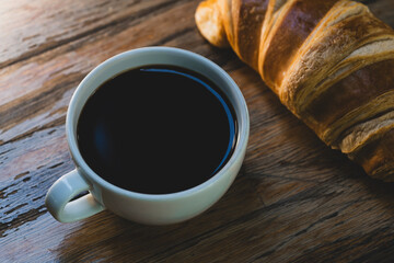 Fresh croissant and hot coffee. Cup of coffee and croissant. Breakfast with coffee and croissant. Cup of coffee with croissant on table.
