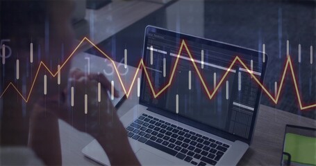 Reviewing chart data on laptop, woman wearing light shirt at wooden desk in office, with smartphone