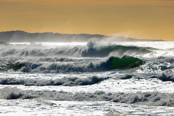 Photograph of waves from the Tasman Sea crashing onto Jones Beach against an orange sky near the town of Kiama Downs in the Illawarra region on the south coast of NSW, Australia.