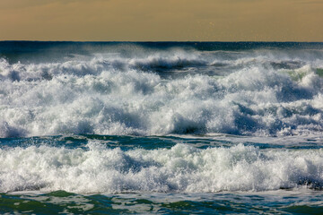 Photograph of waves from the Tasman Sea crashing onto Jones Beach against an orange sky near the town of Kiama Downs in the Illawarra region on the south coast of NSW, Australia.