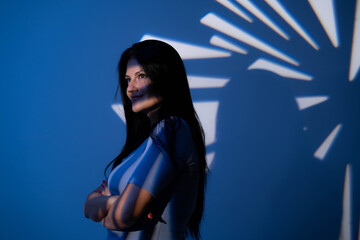 Mysterious woman looking at camera with gobo hard light blue background