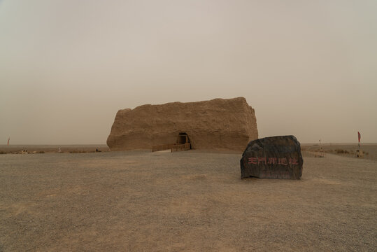Ancient structure at Yumen Pass, China, stands tall in the desert landscape under a hazy sky.