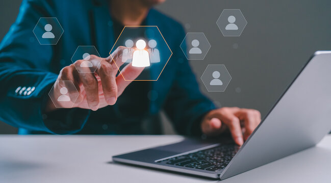 A person interacts with digital icons representing people while using a laptop, showcasing technology and virtual communication.