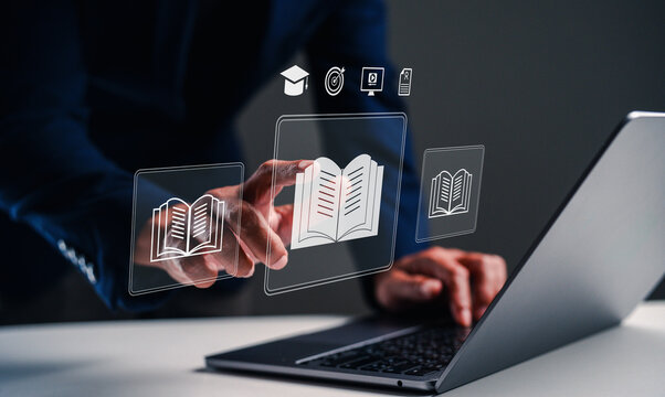 A person interacts with digital book icons on a laptop, symbolizing the integration of technology and education. - Powered by Adobe
