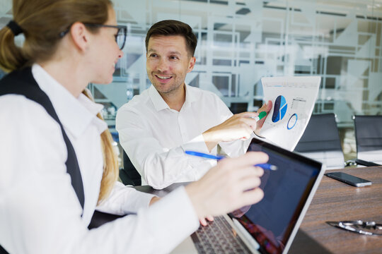 Two business professionals discuss financial data in a modern office setting