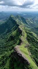 Vast green mountains stretch across the horizon, showcasing rocky peaks and dense forests under a dramatic grey sky