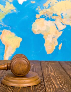 Wooden gavel on a table in front of a world map