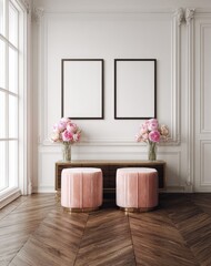 Two empty picture frames hang above a pair of blush pink accent stools in a sophisticated, light-filled interior setting.