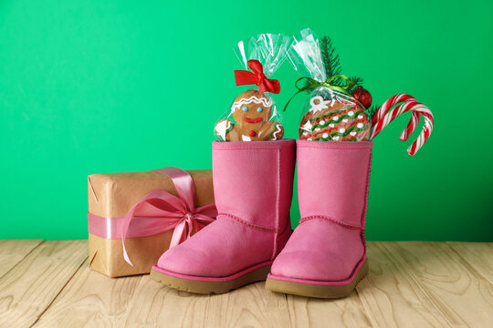 Happy Saint Nicholas day. Boots with sweets, festive decor and gift box on wooden table against green background - Powered by Adobe
