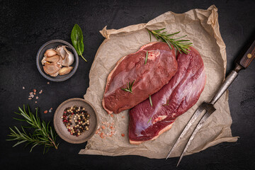 Preparation for cooking raw duck breast with ingredients on dark background, top view. Space for text. High quality photo © petrrgoskov