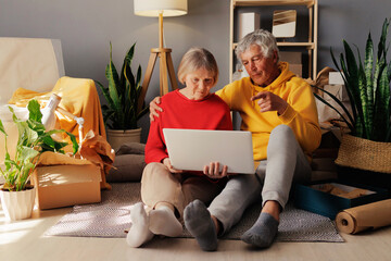 In a bright and welcoming space, a senior couple shares a moment of connection, engaging with their laptop and smiling at each other