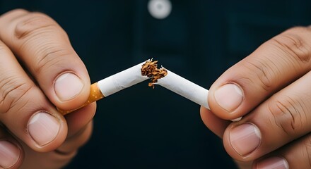 A person's hands are breaking a cigarette in half, symbolizing the decision to quit smoking and embrace a healthier lifestyle.