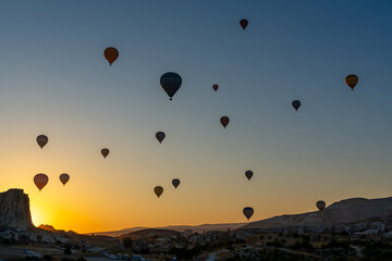 Hot air balloon flying over rocky landscape at sunrise in Cappadocia. Turkey