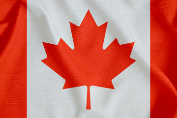 flag of Canada with two red stripes and a maple leaf on a rough canvas with folds