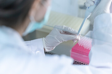 Laboratory technician conducts experiments with test tubes and microscope in a modern research facility
