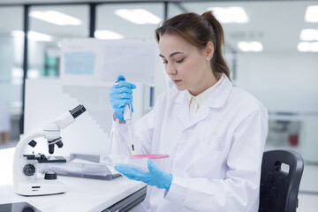 Laboratory technician conducts experiments with test tubes and microscope in a modern research facility