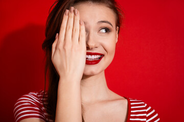 Beautiful young woman with red lipstick smiling and posing against vibrant red background...